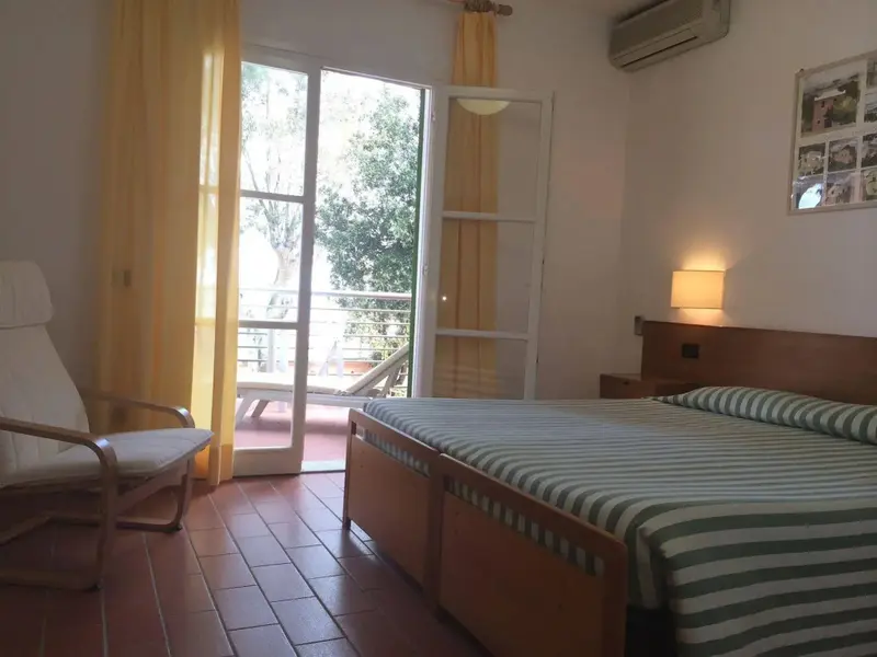 Une chambre lumineuse avec un lit et un accès à un balcon.