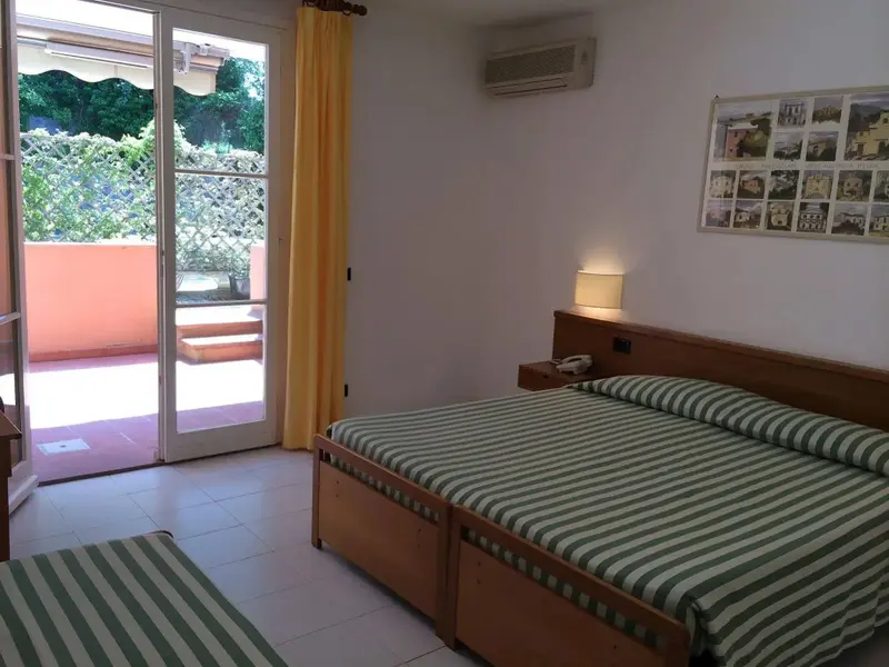 Une chambre lumineuse s'ouvre sur une terrasse ensoleillée.