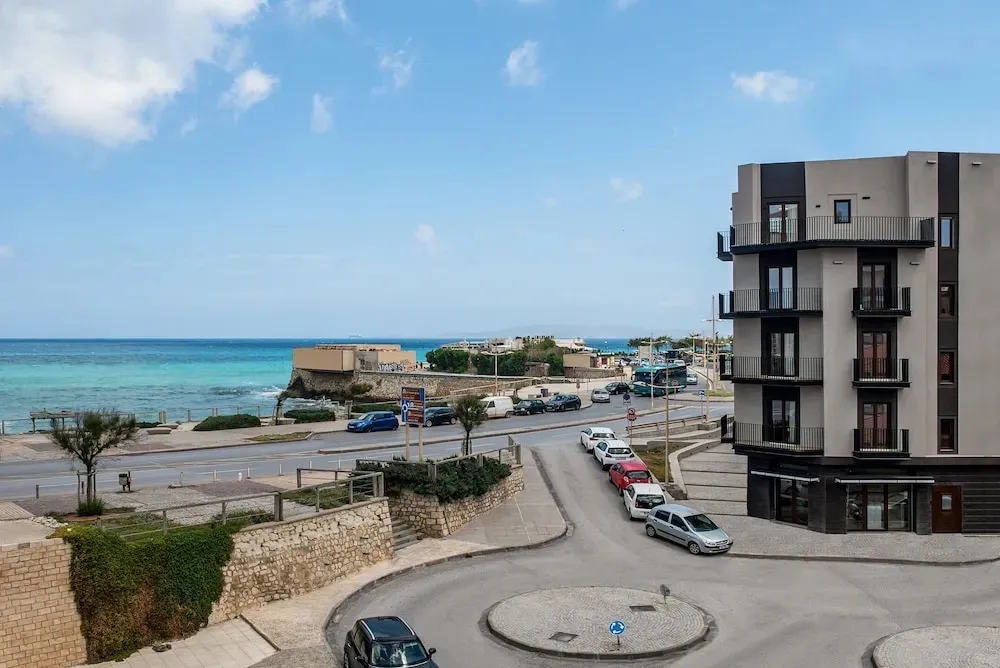Vue d'une route côtière bordée de bâtiments et donnant sur la mer.