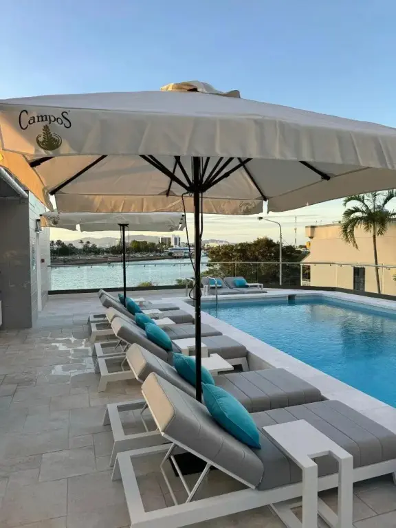 Transats blancs et turquoise disposés autour d'une piscine avec vue sur la mer.