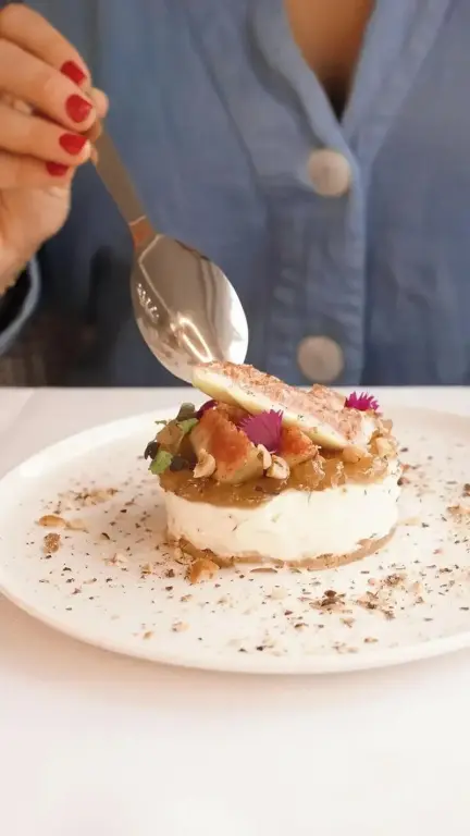 Une personne déguste un dessert à l'aspect raffiné sur une table blanche.