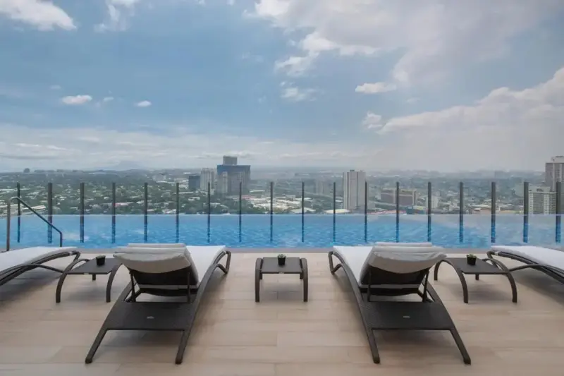 Transats au bord d'une piscine à débordement avec vue sur la ville.