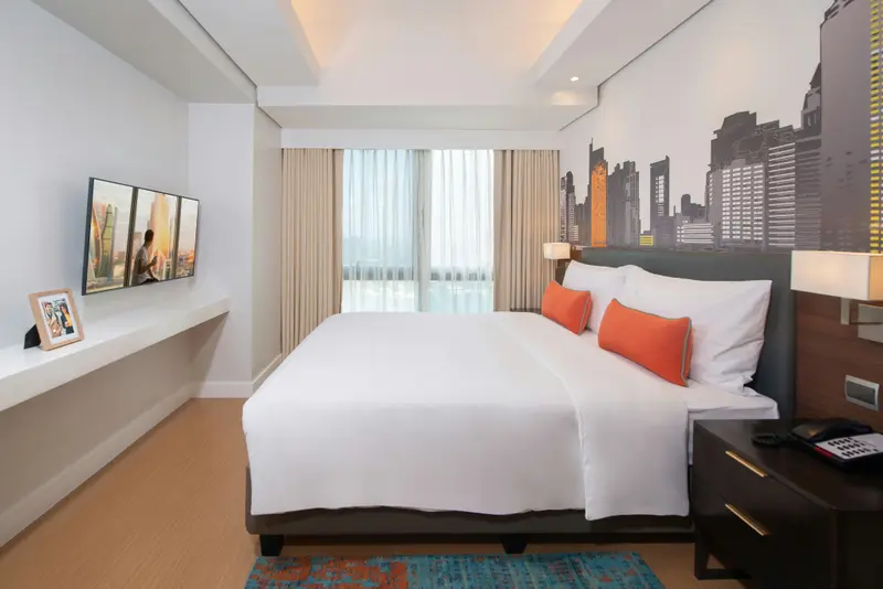 Une chambre lumineuse avec un grand lit et une vue sur la ville.