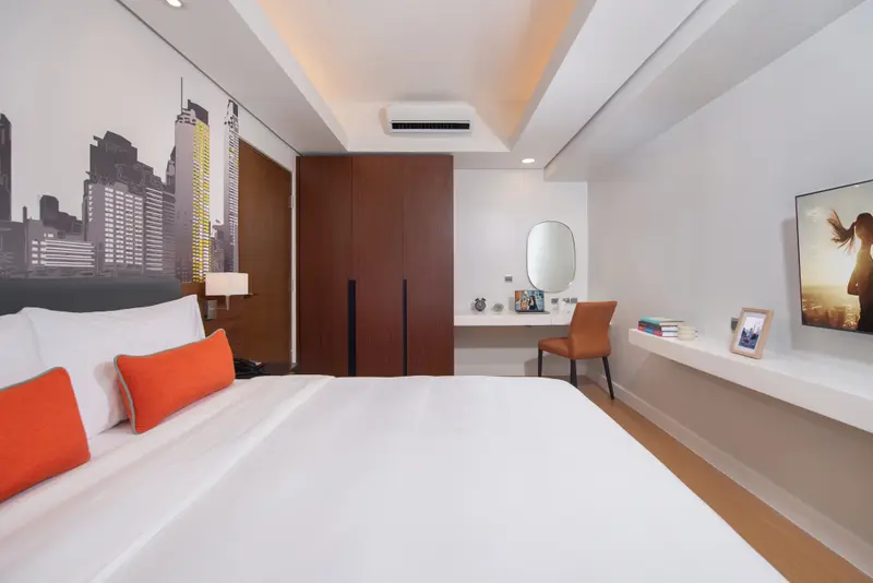 Une chambre lumineuse avec un grand lit et un espace bureau.