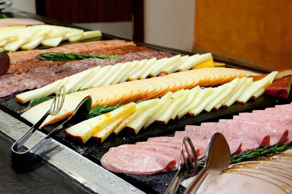 Présentation de charcuterie et de fromages variés sur un buffet.
