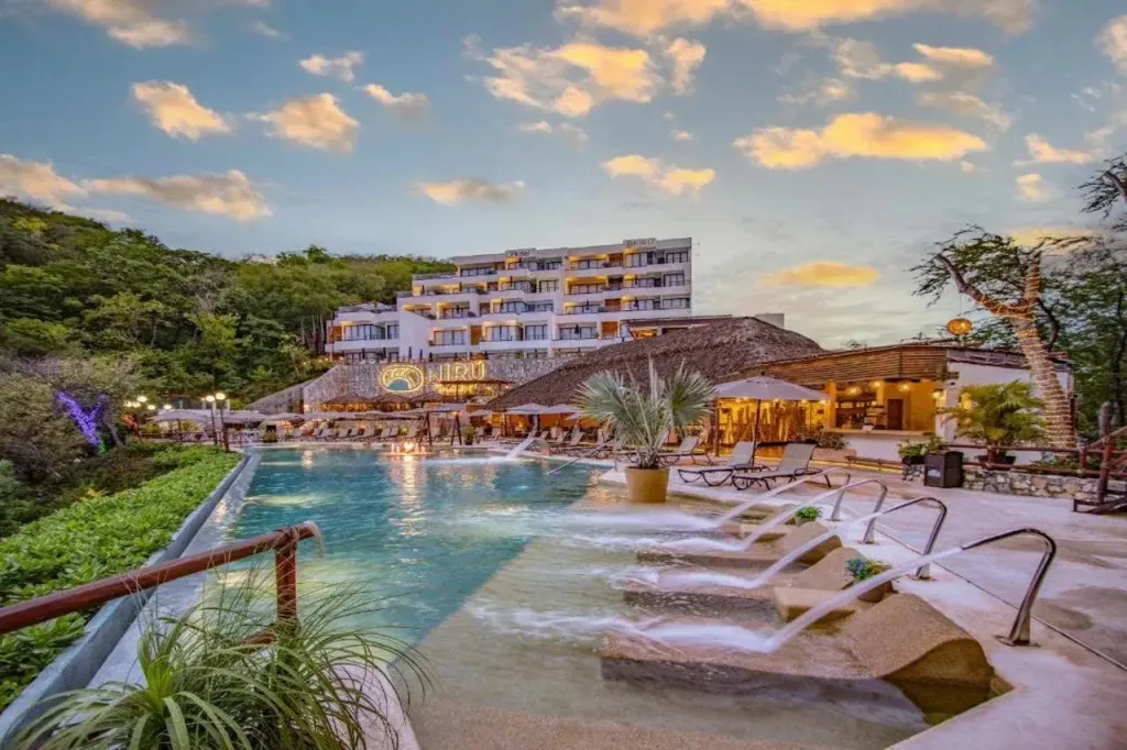 Vue d'un hôtel avec une piscine et des transats au premier plan.