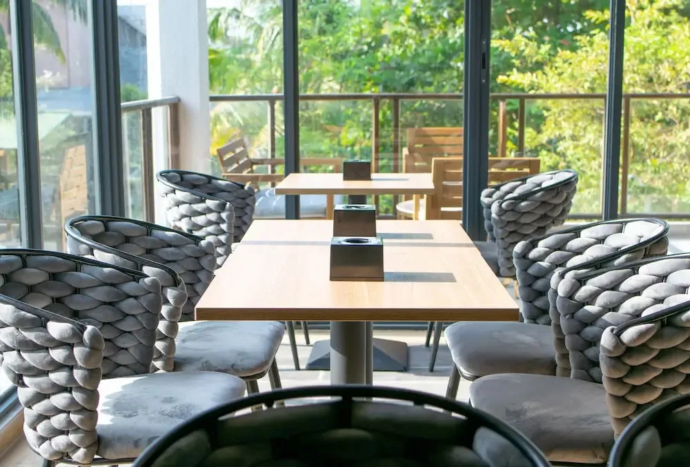 Tables et chaises disposées dans un espace lumineux avec une vue sur la végétation.