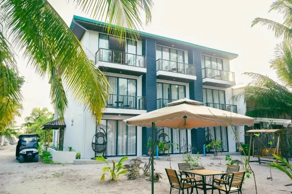 Bâtiment blanc et bleu avec des balcons et des parasols sur une plage de sable.