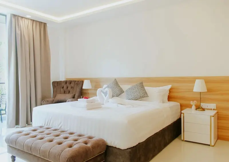 Une chambre lumineuse avec un grand lit recouvert de draps blancs et de décorations.