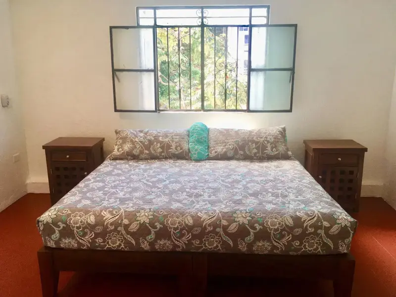Une chambre lumineuse avec un grand lit recouvert d'une couette à motifs.