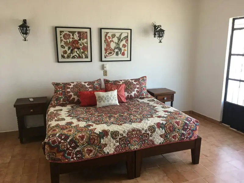 Une chambre lumineuse avec un grand lit recouvert d'une courtepointe colorée et de nombreux oreillers.