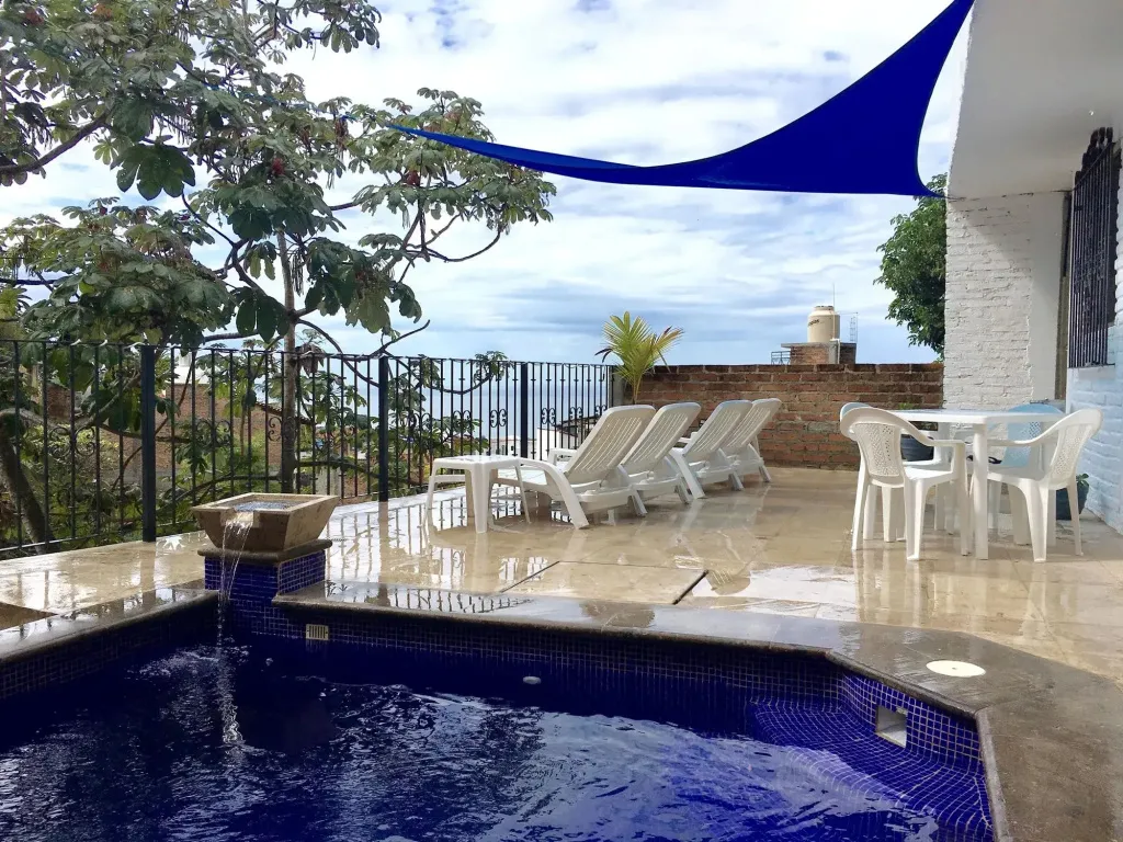 Terrasse avec piscine et mobilier de jardin face à la mer.