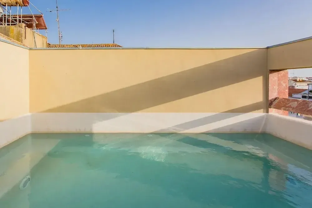 Une petite piscine rectangulaire sur un toit ensoleillé.