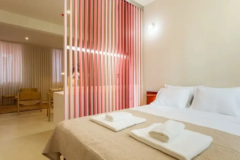 Une chambre lumineuse avec un lit fait et une cloison décorative.