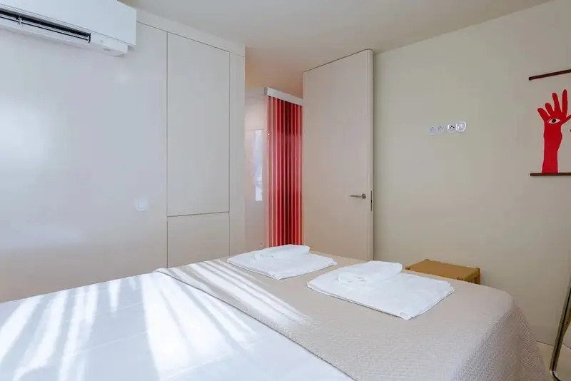 Une chambre lumineuse avec un lit double et un rideau rouge.