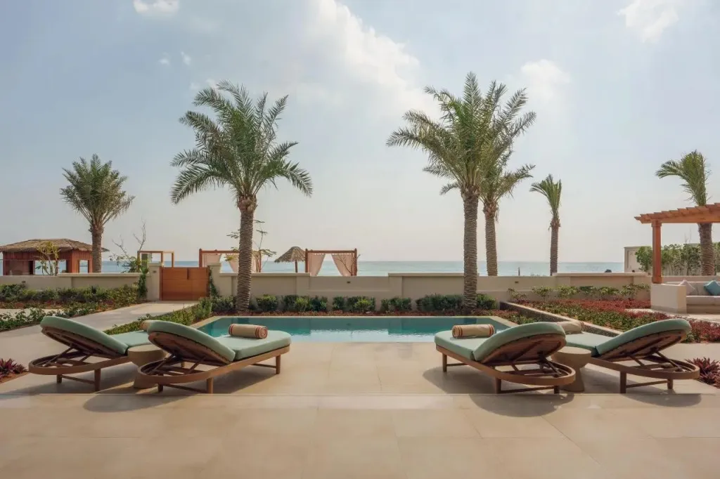 Terrasse avec chaises longues et piscine face à la mer.