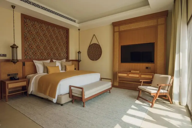 Une chambre lumineuse avec un grand lit et un décor mural en bois.