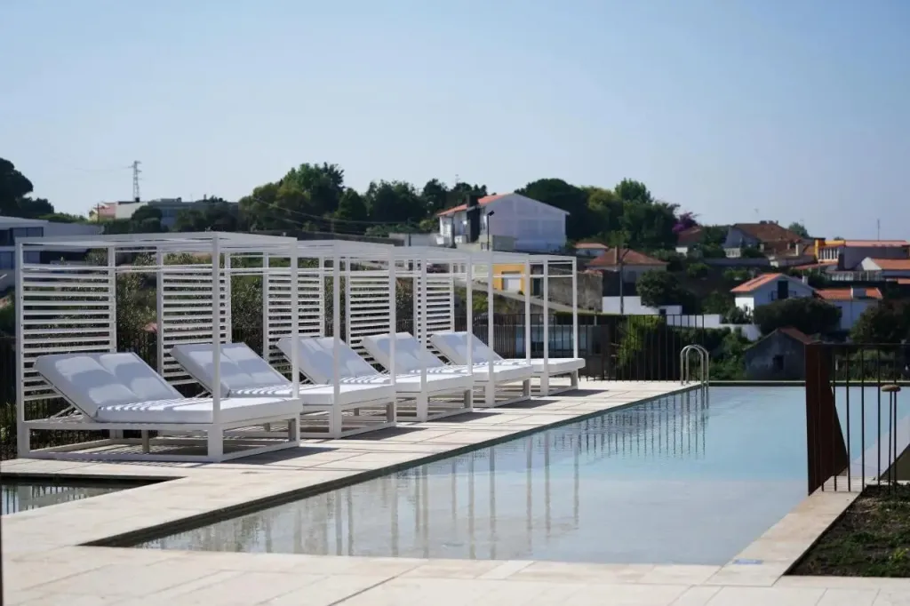 Transats blancs alignés au bord d'une piscine rectangulaire.