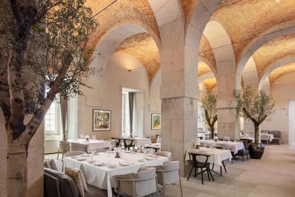 Une salle à manger élégante avec des tables nappées et des arches en pierre.