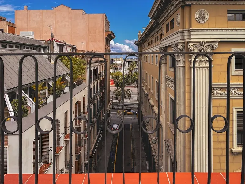 Vue sur une rue urbaine depuis un balcon en fer forgé.