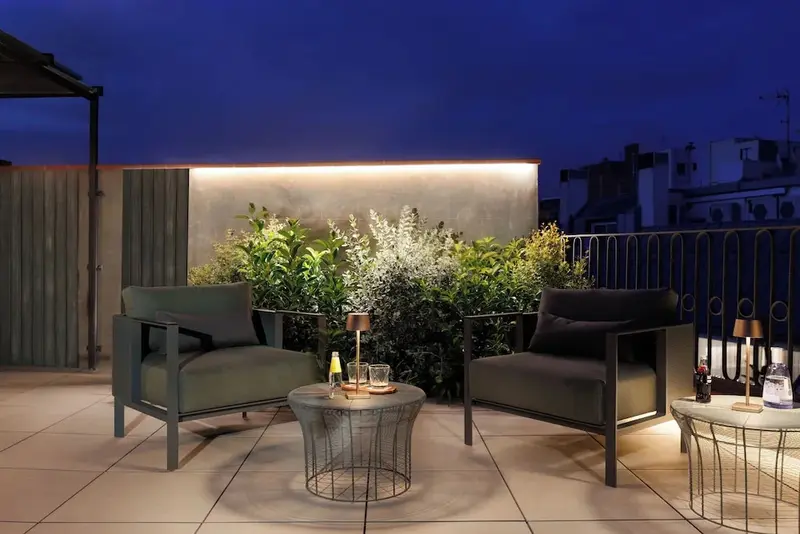 Espace extérieur aménagé avec des fauteuils et des tables basses éclairés.