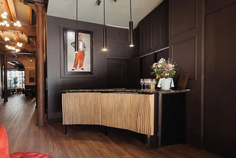 Un comptoir d'accueil en bois clair se trouve dans un hall d'entrée décoré de boiseries sombres.