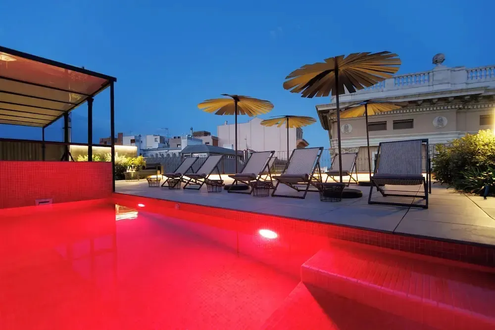 Terrasse avec piscine et chaises longues éclairées.