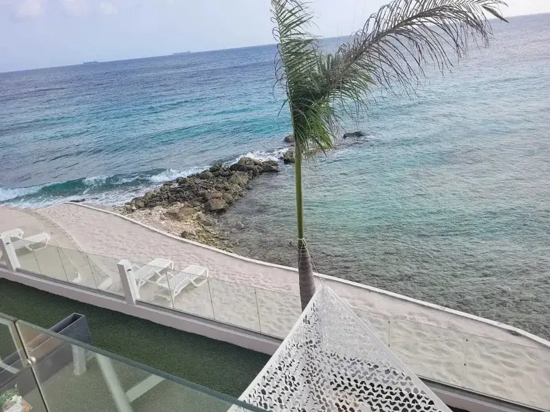 Vue aérienne d'une plage de sable blanc bordée de chaises longues et d'une mer turquoise.