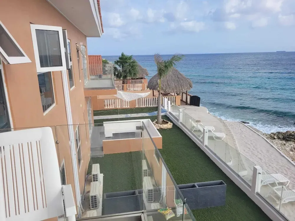 Terrasse avec mobilier blanc donnant sur une plage de sable et la mer.