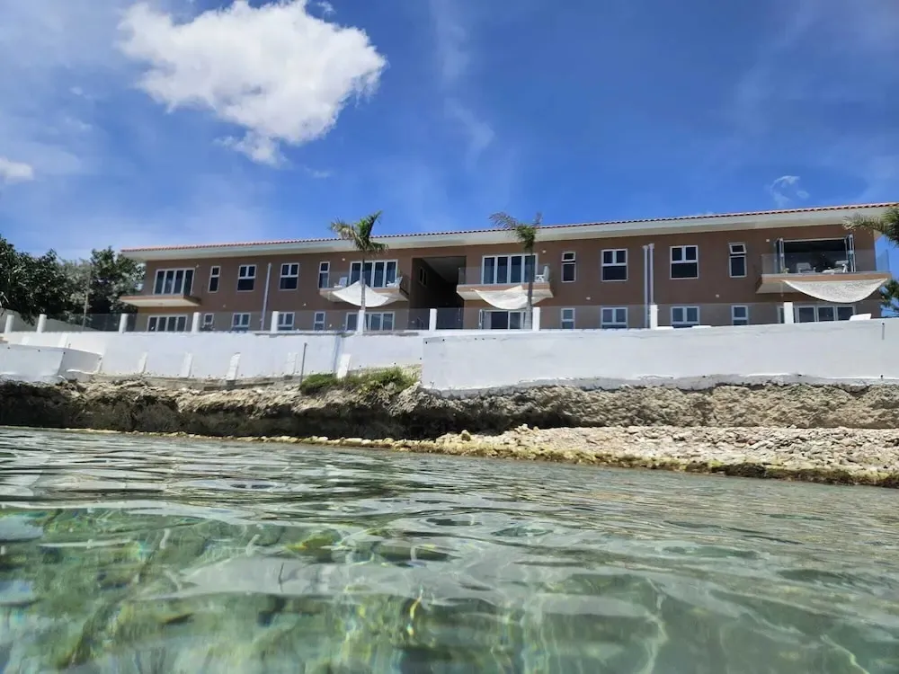 Bâtiment beige avec balcons et vue sur la mer turquoise.