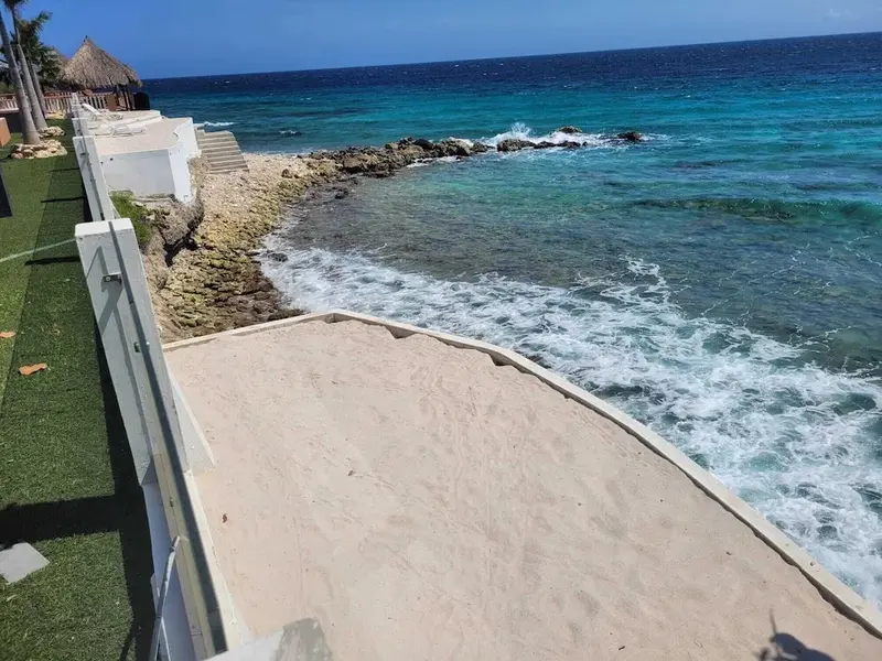 Vue sur une côte rocheuse avec une mer turquoise et une plage de sable.