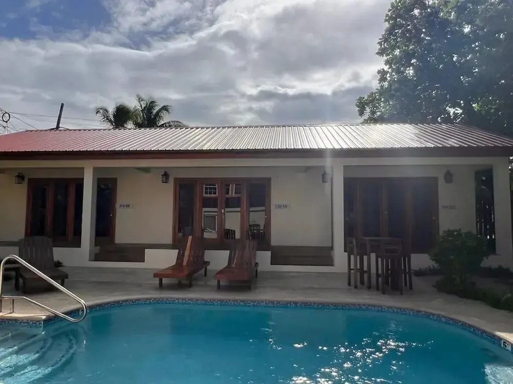 Bâtiment beige avec des transats près d'une piscine bleue.