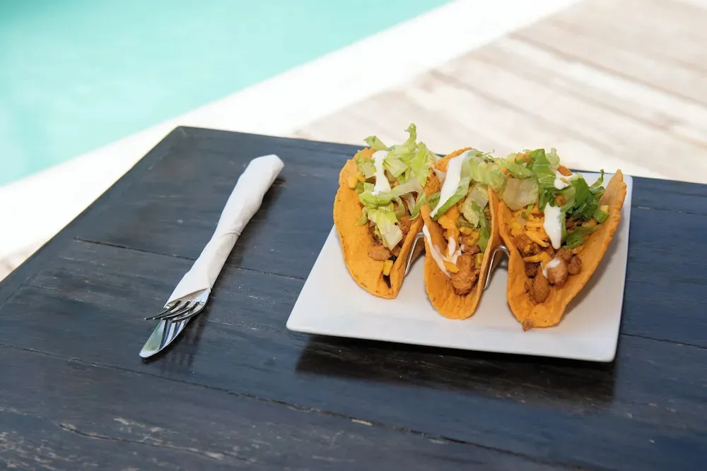 Assiette de tacos sur une table sombre près d'une piscine.