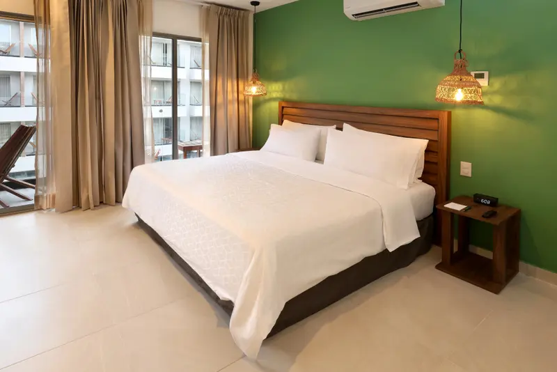 Une chambre lumineuse avec un grand lit et un mur vert.