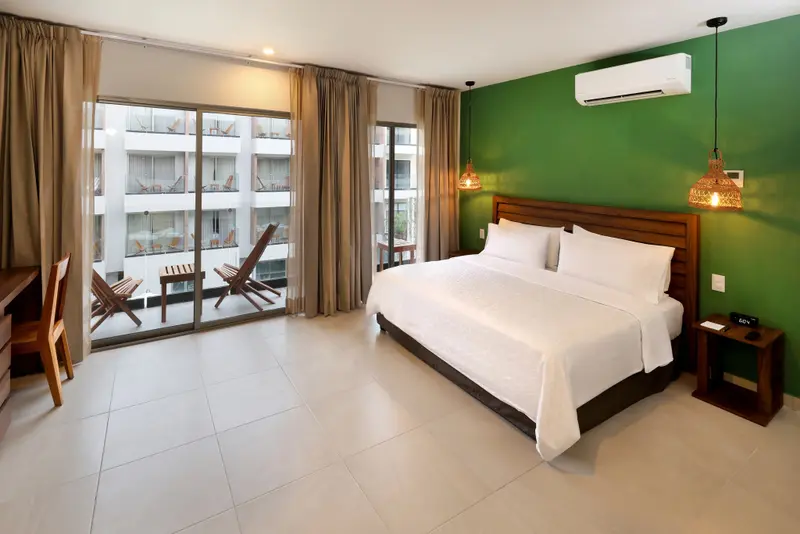Une chambre lumineuse avec un grand lit et un accès à un balcon.