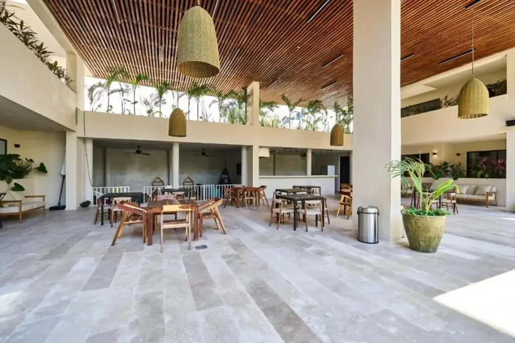 Espace de restauration lumineux avec tables en bois et suspensions en fibres naturelles.