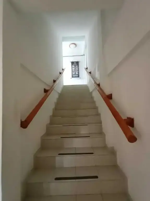 Un escalier mène vers le haut dans un couloir éclairé.