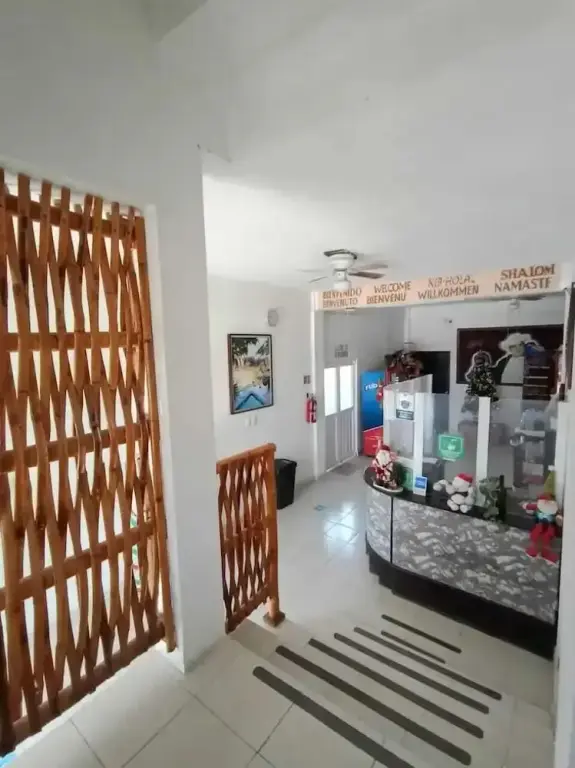 Un comptoir d'accueil en bois est visible dans un hall lumineux.