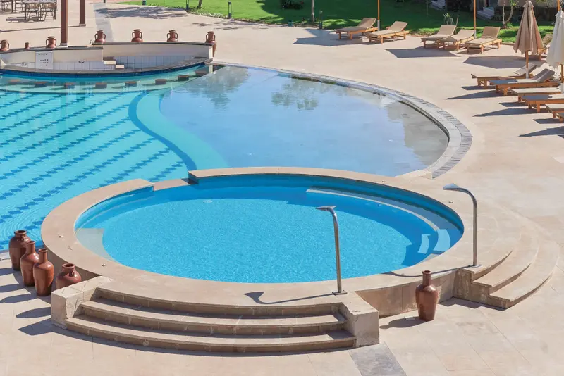 Piscine extérieure avec espace de détente et transats.