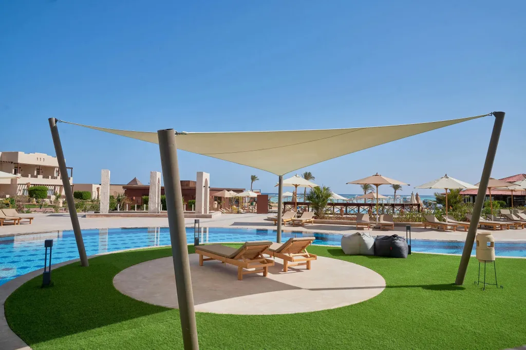 Espace de détente avec chaises longues près d'une piscine ensoleillée.
