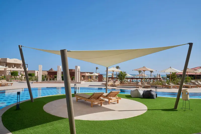 Espace de détente avec chaises longues près d'une piscine ensoleillée.