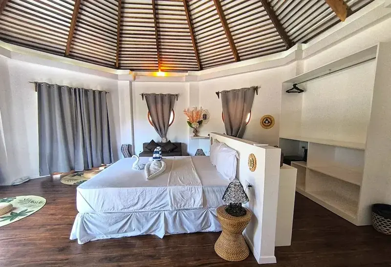 Une chambre lumineuse avec un grand lit recouvert de draps blancs et décoré de serviettes en forme de cygnes.