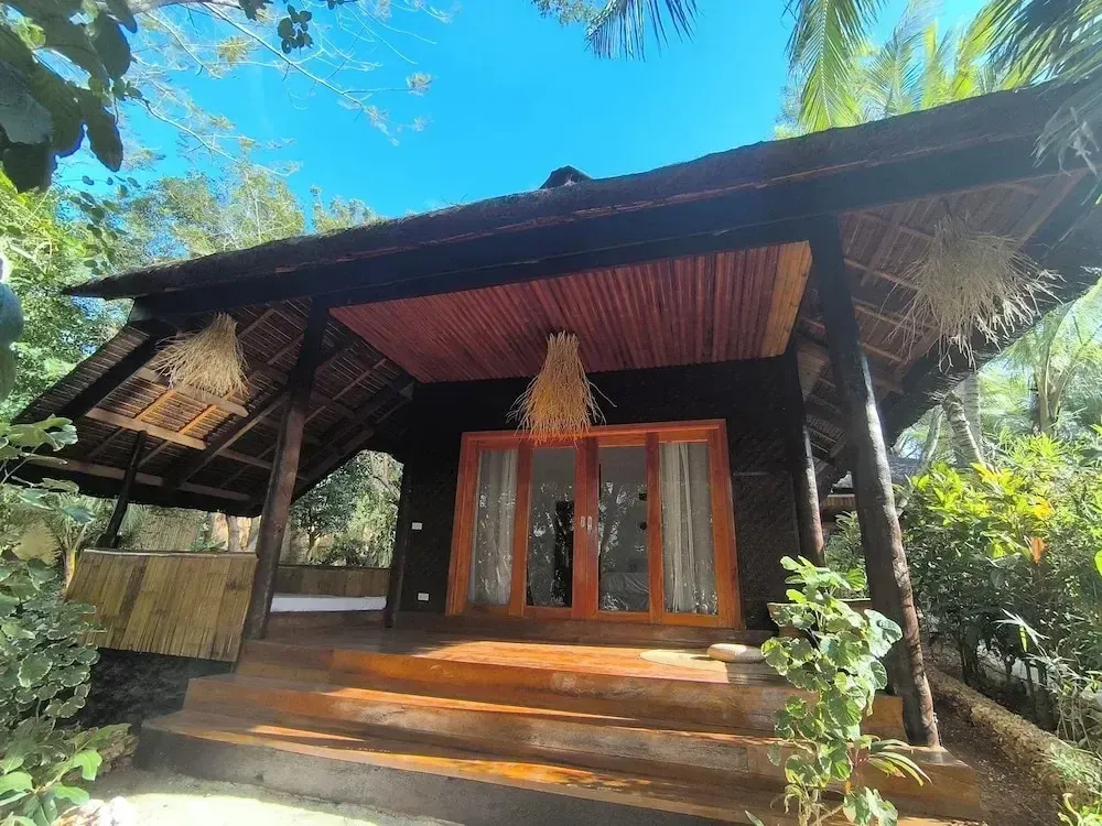 Une cabane en bois sur pilotis avec une terrasse ensoleillée.