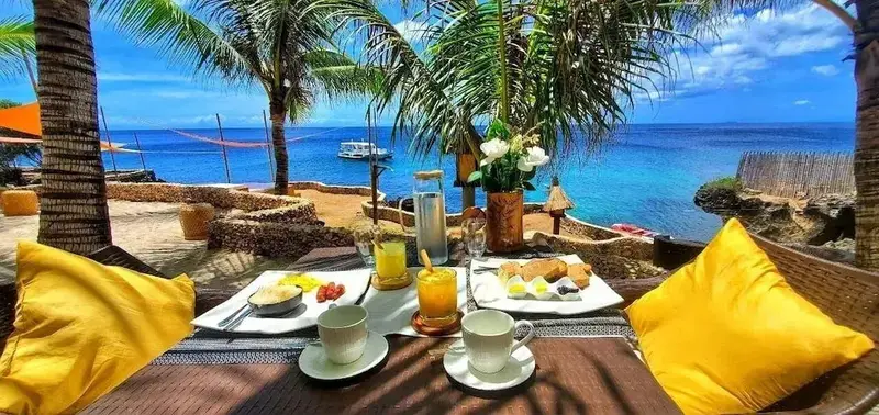 Une table est dressée avec un petit-déjeuner face à la mer.