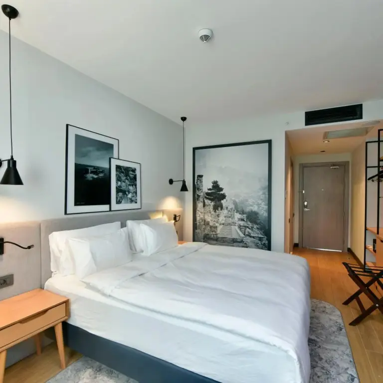 Une chambre lumineuse avec un grand lit et des tableaux décoratifs.