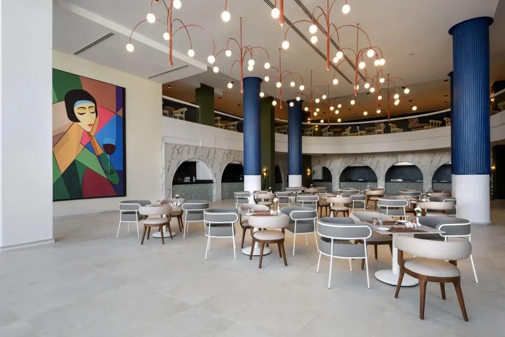 Une salle lumineuse est aménagée avec des tables et des chaises pour les repas.