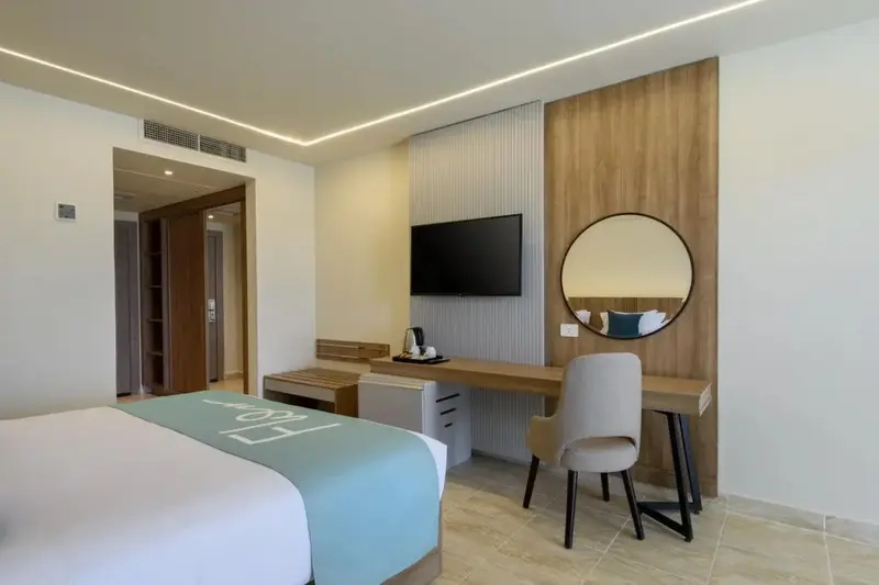 Une chambre lumineuse avec un lit, un bureau et une télévision murale.
