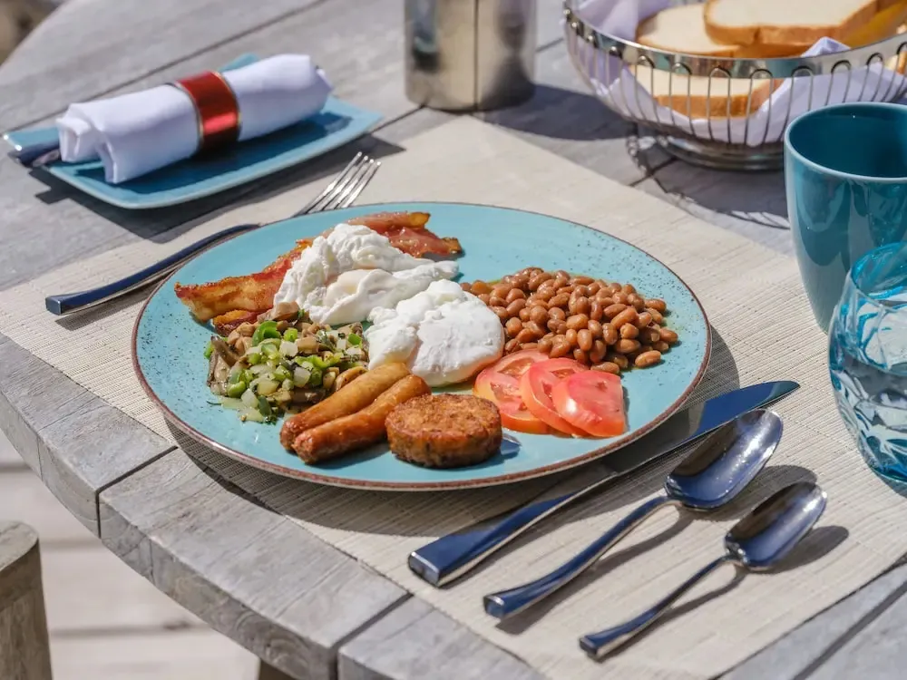 Un copieux petit-déjeuner anglais est servi sur une table en bois.