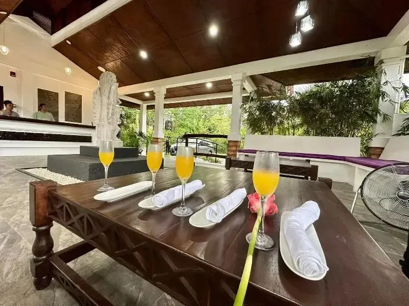 Une table en bois est dressée avec des verres de jus d'orange et des serviettes.