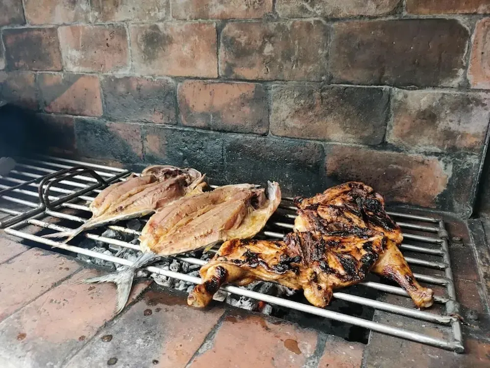 Volaille et poisson grillés sur un barbecue en briques.